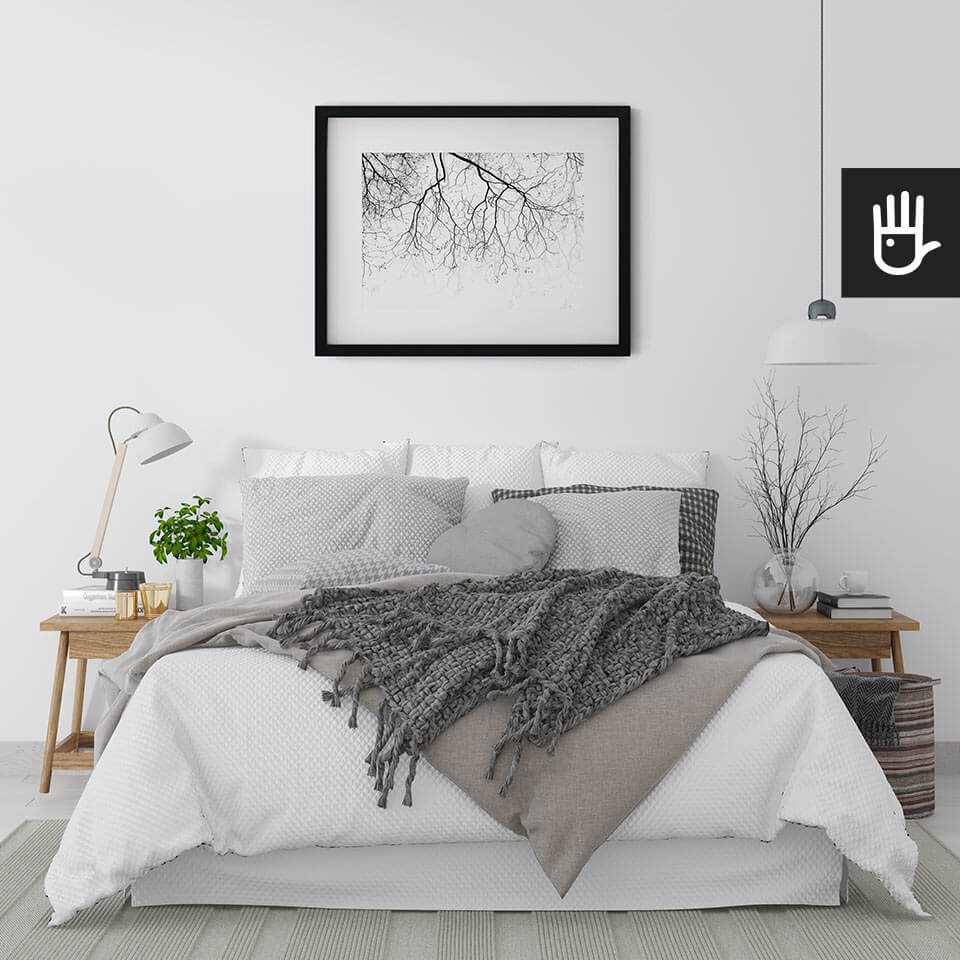 wnętrze sypialni w jasnych barwach z plakatem Gałęzie na wietrze nad łóżkiem