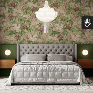 Stylowa sypialnia z szarym łóżkiem ze ścianą z akcentami zieleni i tapetą z dużymi fioletowymi kwiatami.
