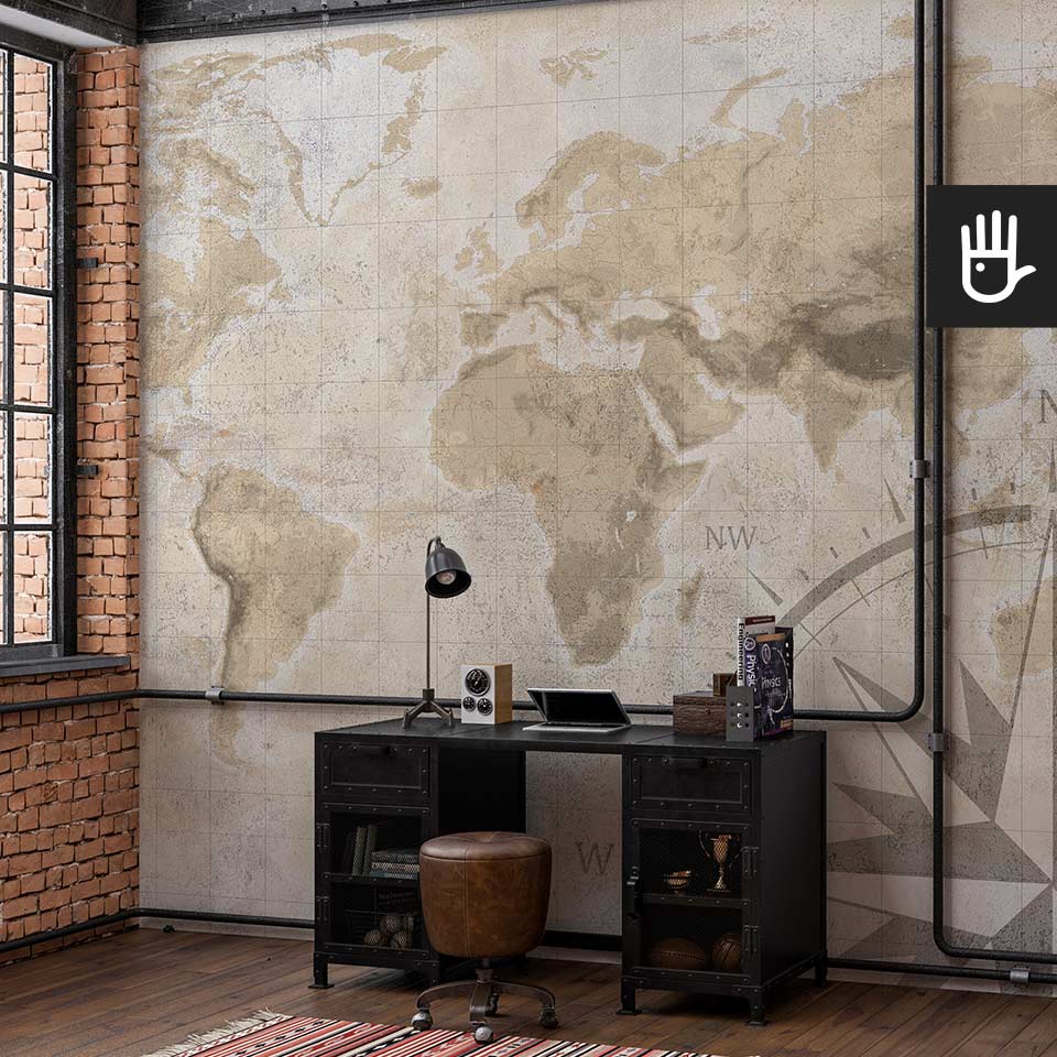 Wnętrze w stylu loftowym z metalowym biurkiem oraz ścianą na której znajduje się fototapeta mapa świata ze strukturą betony w ciepłych odcieniach beżu i brązu.