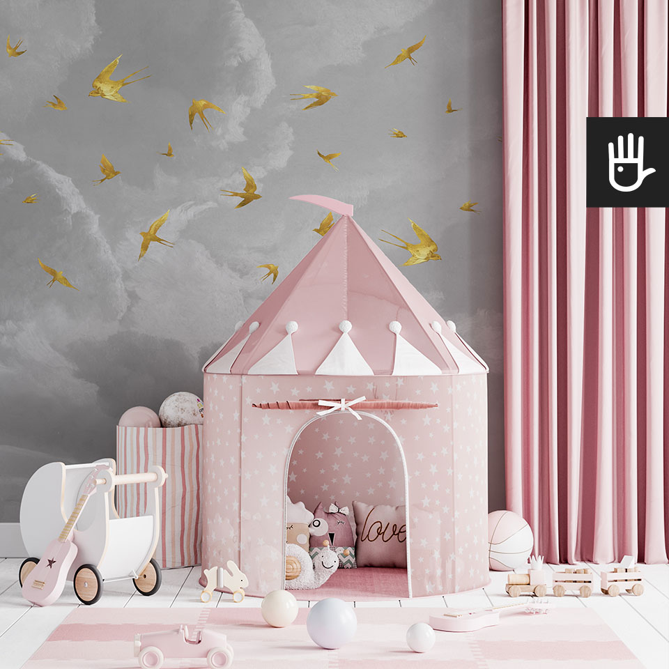 Pokój małej księżniczki z różowym zamkiem i szarą ścianą w formie fototapety z szarymi chmurami na których tle latają złote jaskółki.