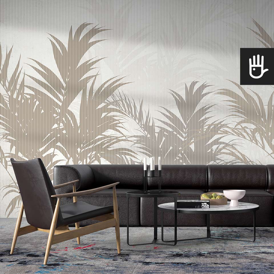 Salon ze skórzaną kanapą na tle ściany z dekoracją, którą jest fototapeta ścienna Letnie cienie z motywem tropikalnych liści i detalem w formie szarych prążków