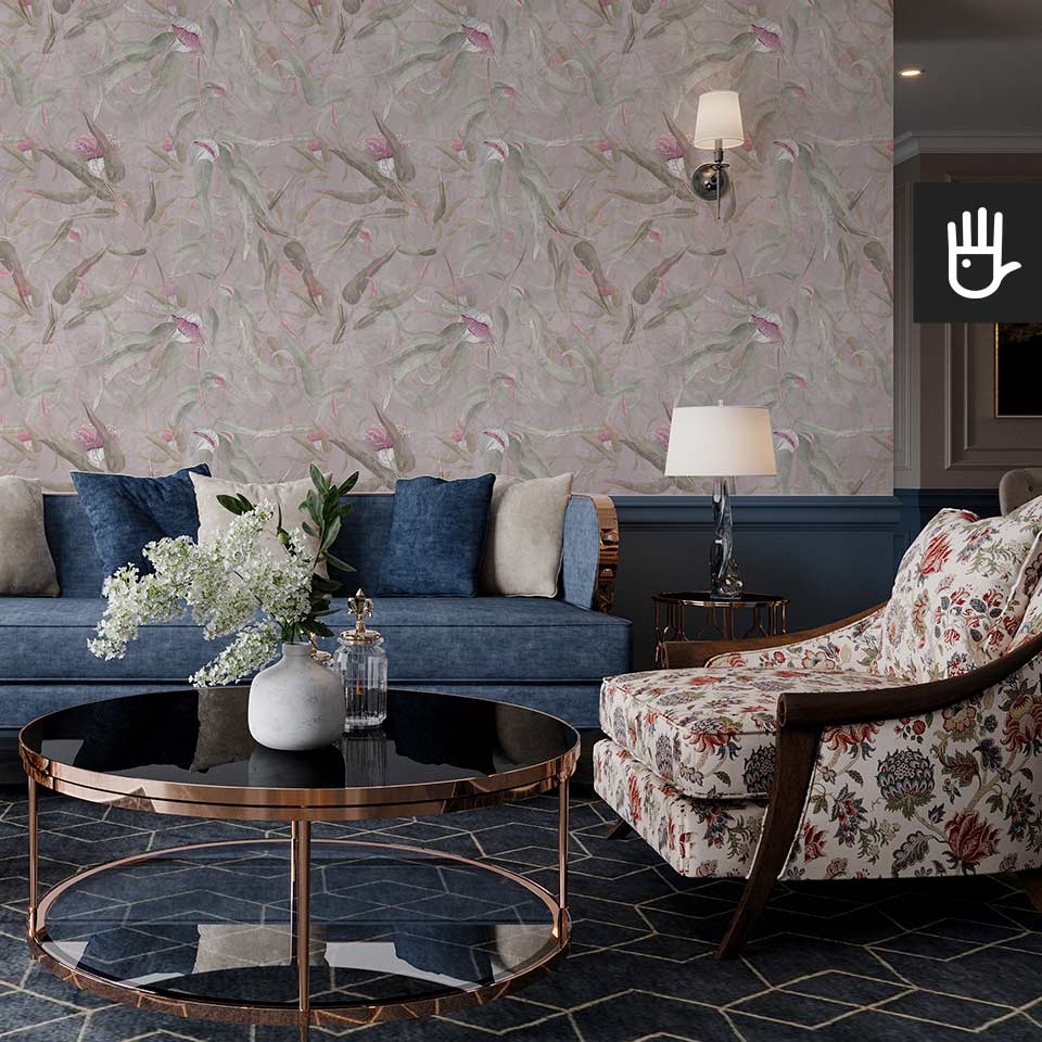 Salon w stylu Hampton z kolorową kanapą na tle ściany pokrytej łososiową tapetą ścienną z malowanymi różowymi kwiatami eukaliptusa i zielonymi listkami.