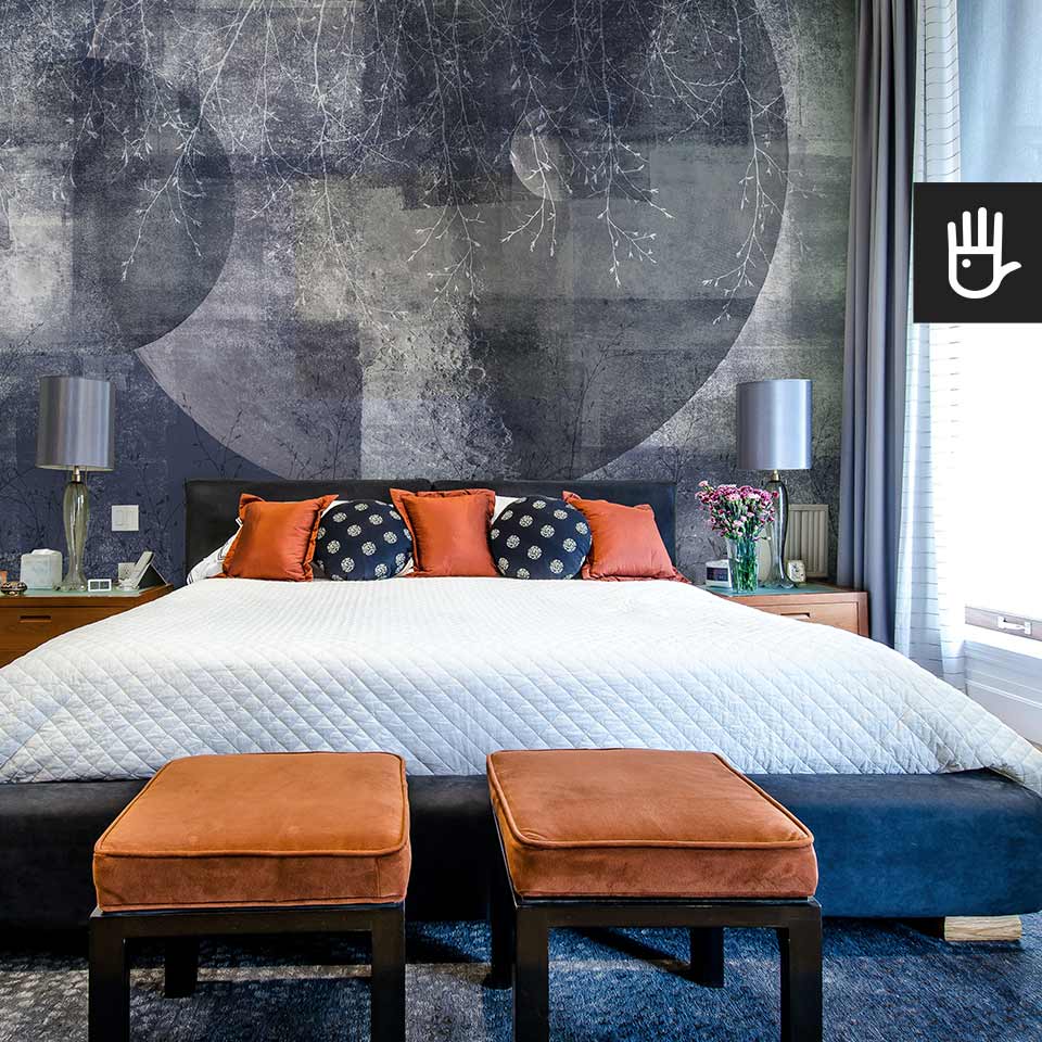 Sypialnia w stylu hampton z granatowym łóżkiem kontynentalnym na tle fototapety ściennej Granatowy księżyc z motywem delikatnych gałęzi.