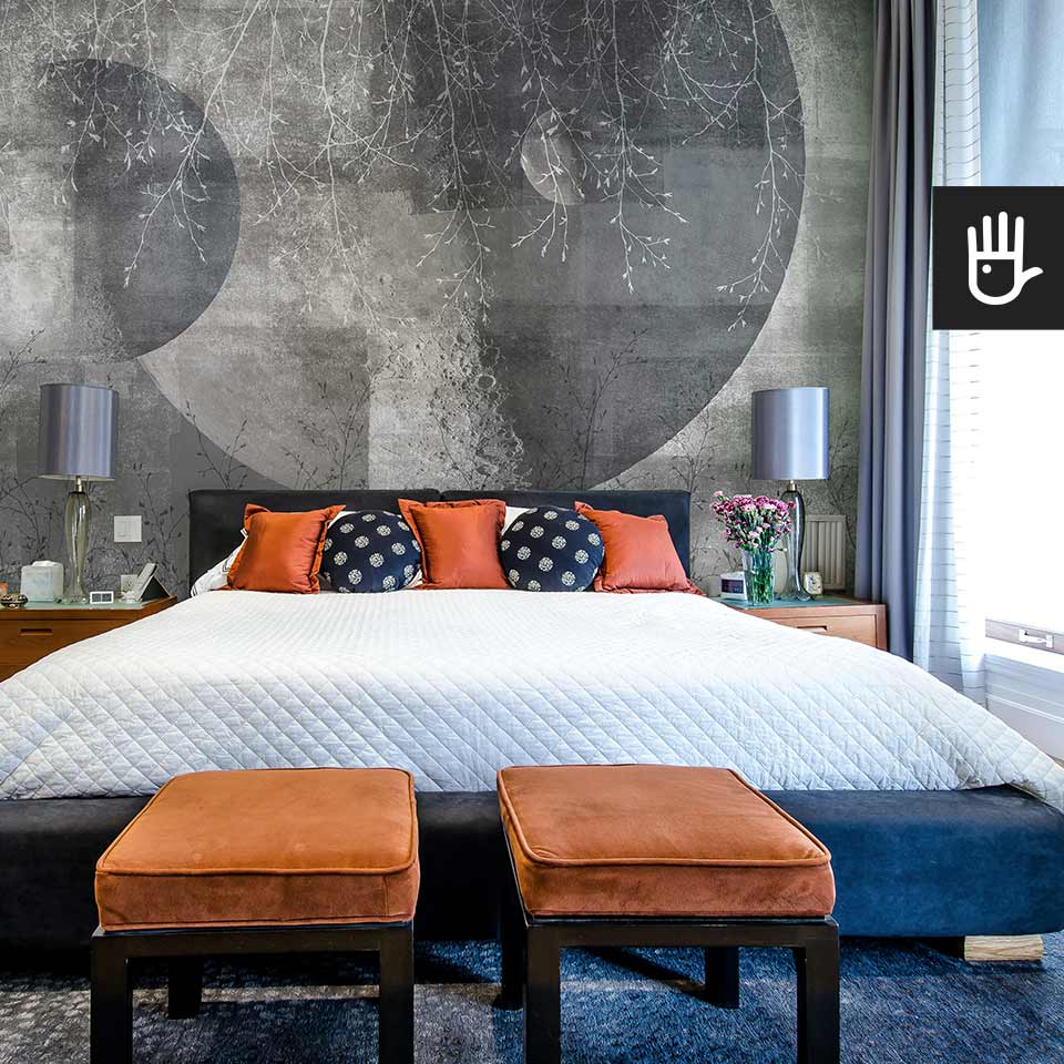Sypialnia w stylu hampton z granatowym łóżkiem kontynentalnym na tle fototapety ściennej Srebrny księżyc z motywem delikatnych gałęzi.