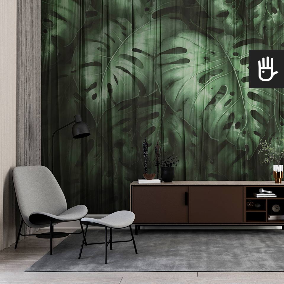 Elegancki gabinet z dekoracyjną ciemną fototapetą Monstera z dużymi, zielonymi, tropikalnymi liśćmi spowitymi przeźroczystym materiałem na ścianie za komodą.