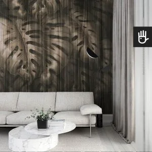 Nowoczesny salon we włoskim stylu z beżową kanapą na tle ciemnej fototapety Złota monstera z dużymi liśćmi egzotycznej rośliny w odcieniach brązu wyłaniających się zza delikatnej, prześwitującej zasłony.