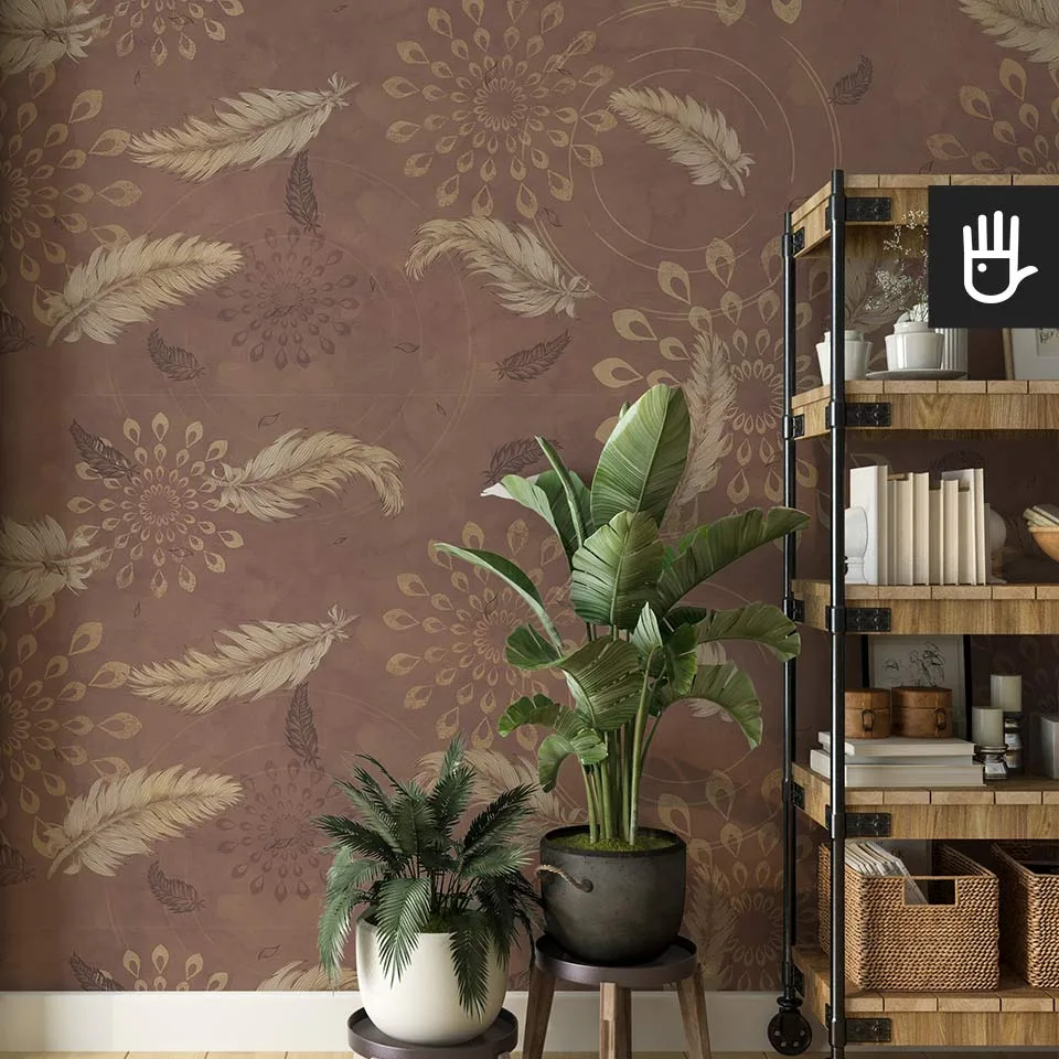 Drewniany regał zastawiony dekoracjami w stylu boho obok dekoracyjnych kwiatów na tle brązowej tapety w delikatne piórka ze wzorem mandali