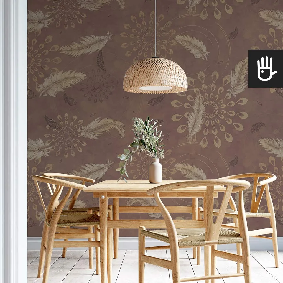 Drewniany stół jadalniany w stylu boho z wiklinową lampą wiszącą na tle tapety w kolorze brązu z delikatnymi piórkami