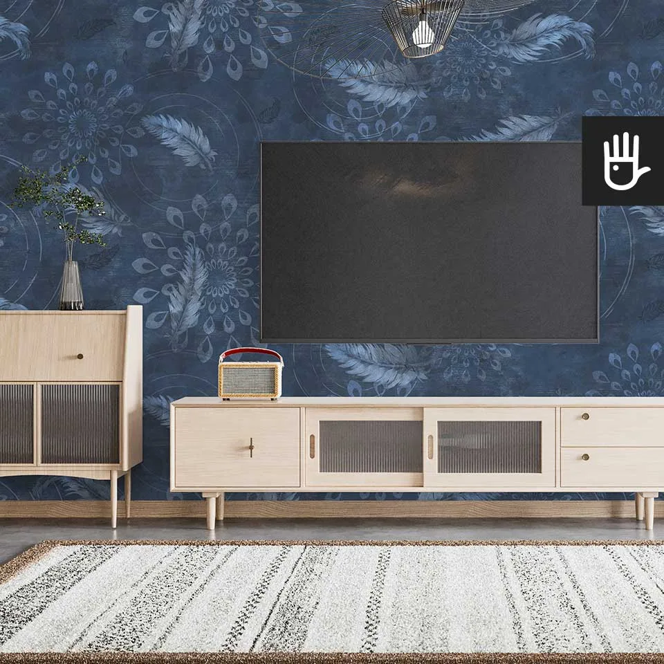 Salon urządzony w stylu boho z drewnianą szafką rtv i dywanem. Na ścianie telewizor na tle tapety w piórka
