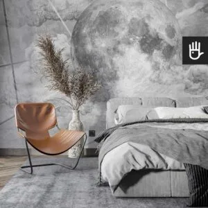 Przytulna sypialnia z dużym szarym łóżkiem skórzanym fotelem i dodatkami boho na tle fototapety z księżycem