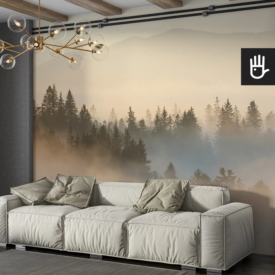 Salon w stylu boho z beżową kanapą ozdobioną zielonym poduszkami na tle fototapety ze wschodem słońca nad mglistm lasem