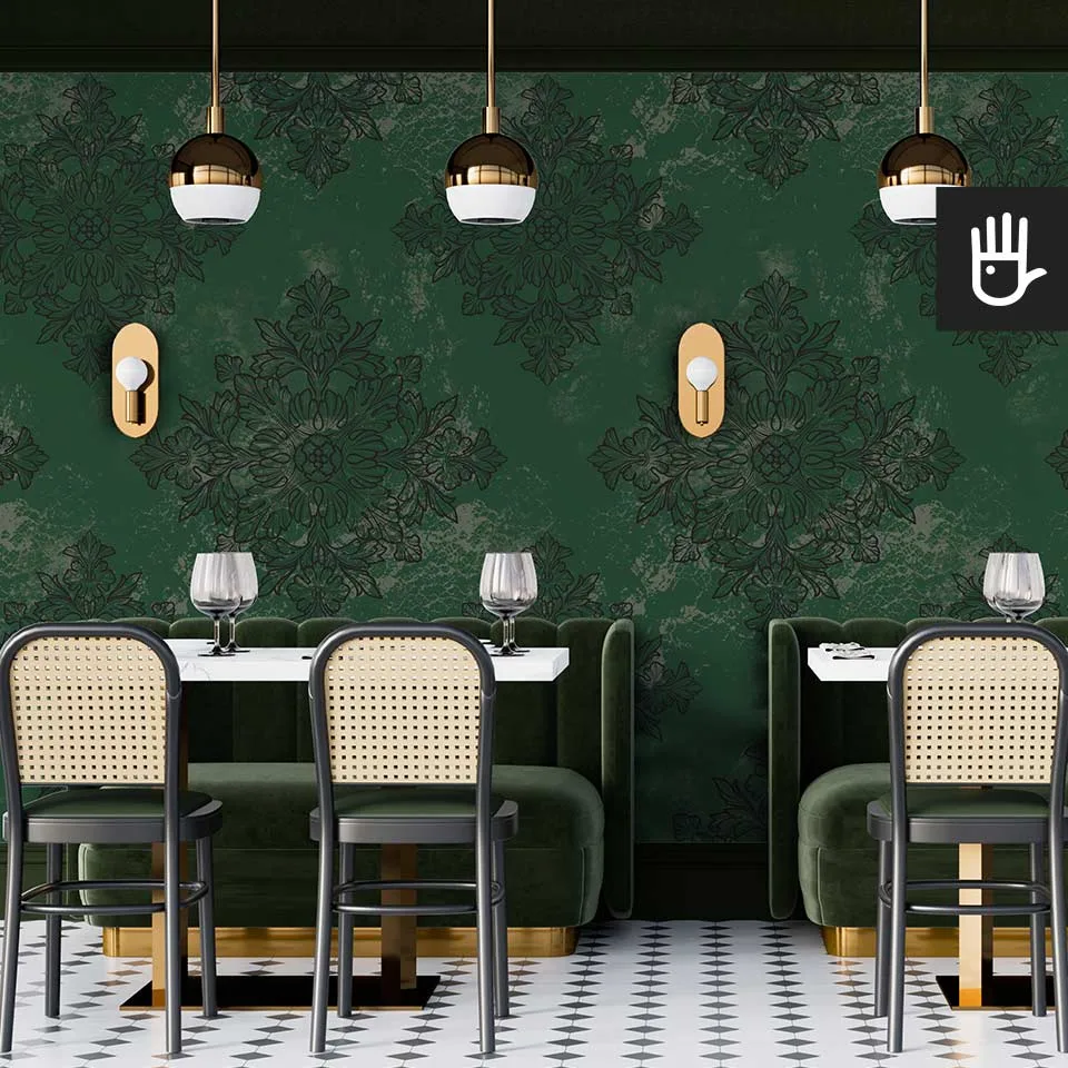 Restauracja w stylu retro z zielonymi kanapami i krzesłami z oparciami z ratanu na tle ciemnej tapety w geometryczny wzór