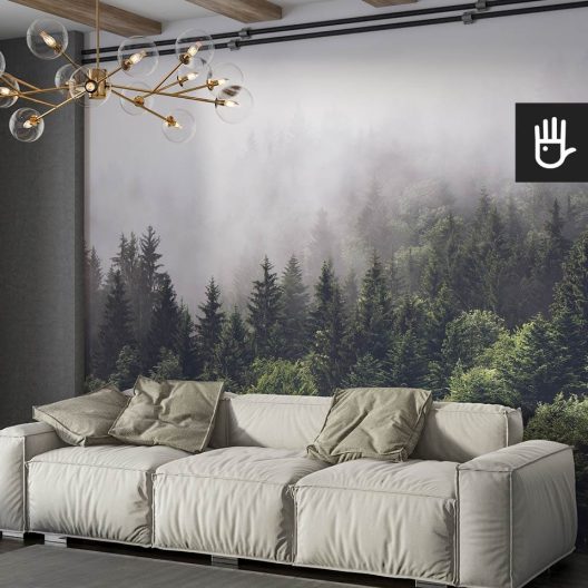 Przytulny salon z dużą beżową kanapą i dekoracyjnymi zielonymi poduszkami na tle fototapety z lasem