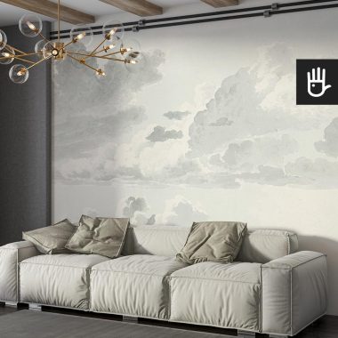 Salon w stylu boho z beżową kanapą ozdobioną zielonym poduszkami na tle fototapety z akwarelowymi chmurami