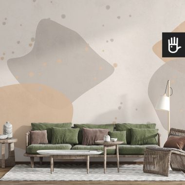 Salon w stylu boho z wiklinowym fotelem i zieloną kanapą na tle fototapety w beżowe i brązowe plamy