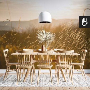 Fototapeta Słońce w trawie z widokiem gór na ścianie w jadalni z drewnianym stołem w górskim klimacie.