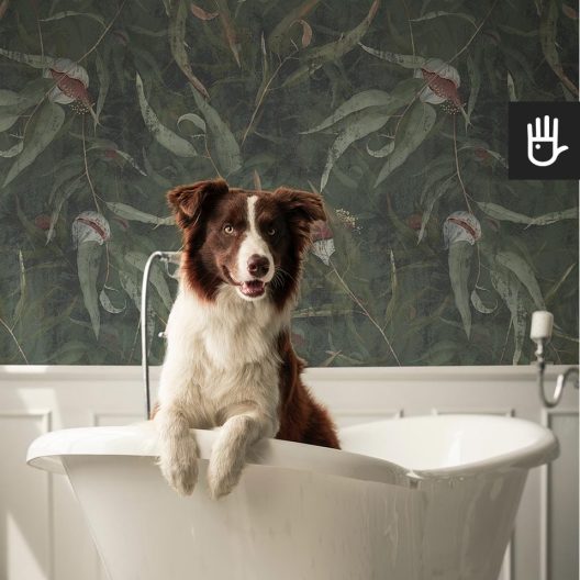 Klasyczna łazienka z wanną wolnostojącą, z białymi sztukateriami i dekoracją ściany, którą jest tapeta Kwiaty eukaliptusa w różowym kolorze na ciemnozielonym tle.