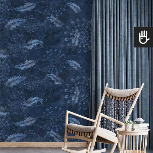 Bujany fotel do czytania w stylu boho z dekoracyjnym stolikiem z książkami na tle tapety w granatowym kolorze z delikatnym wzorem