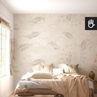 Słoneczna sypialnia urządzona w stylu boho z wieloma dodatkami. Wszystko utrzymane w beżowo-brązowej tonacji. Na tle tapety boho w delikatne piórka i geometryczny kształt.
