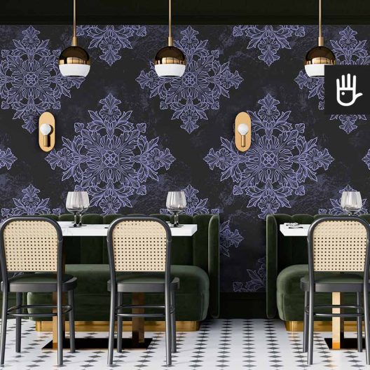 Restauracja w stylu retro z zielonymi kanapami i krzesłami z oparciami z ratanu na tle ciemnej tapety w geometryczny wzór