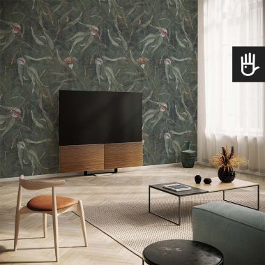 Modna tapeta ścienna Kwiaty eukaliptusa na ścianie telewizyjnej z tłem w kolorze butelkowej zieleni na którym znajdują się malowane kwiaty i zielone liście.
