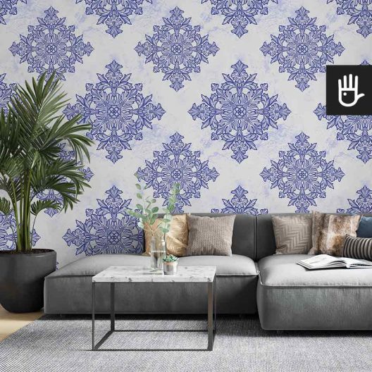 Jasny salon z szarą kanapą i ozdobnym kwiatem palmą ze stolikiem z imitacji marmuru na tle tapety w geometryczny wzór